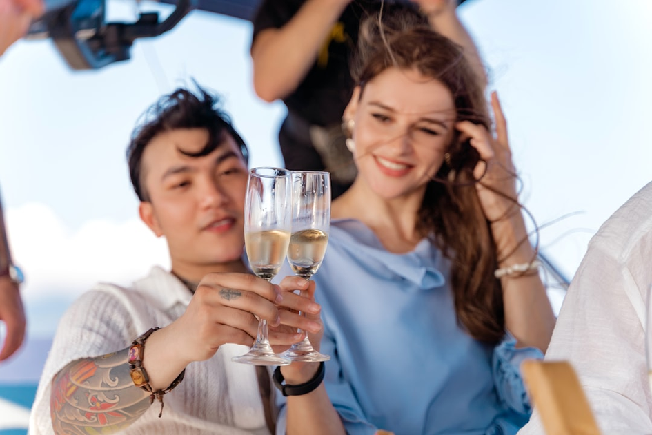 Elegant couple toasting with champagne on private villa terrace overlooking tropical beach at sunset