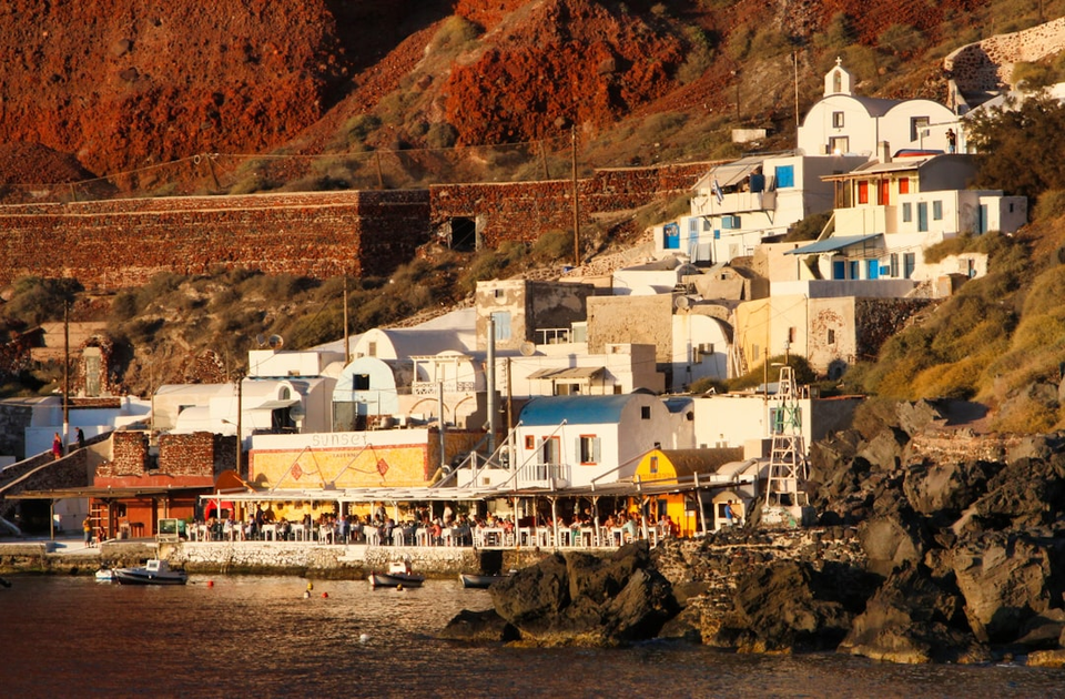 Santorini cliffside luxury destination with white buildings and blue domes overlooking Aegean Sea