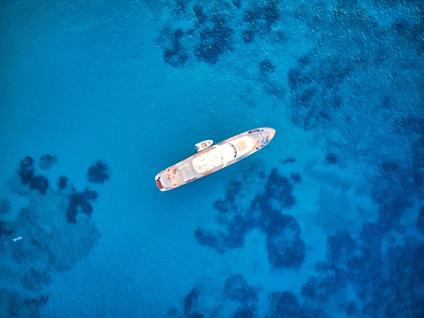Luxury superyacht cruising through Mediterranean waters at sunset with multiple decks and infinity pool