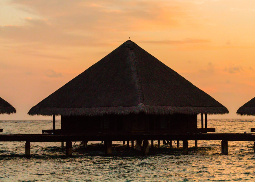 Luxury overwater bungalow with infinity pool in the Maldives at sunset with turquoise lagoon waters
